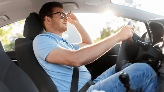 Motorista com óculos ao volante em condição de sol forte